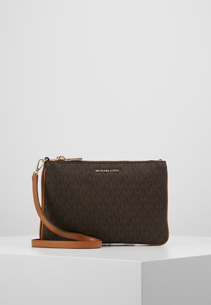 Sac bracelet Michael Kors marron avec fermeture éclair dorée et logo, bandoulière en cuir fauve et surface à motifs, placé sur un socle blanc.