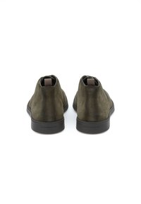 Bottes de cheville en suede vert olive foncé avec une texture lisse, un bout arrondi et des accents latéraux élastiques. Caractéristiques d'une semelle en caoutchouc noir.