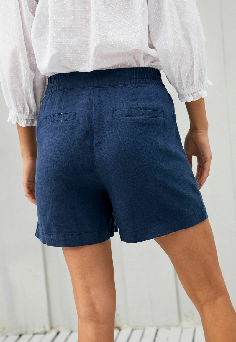 Shorts in lino blu navy con vita elastica, due tasche posteriori e vestibilità morbida, caratterizzati da un orlo risvoltato e una texture liscia.