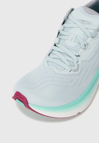 Baskets de course bleu clair avec une tige en mesh, une texture ondulée, et une semelle turquoise et rose avec un design à bout arrondi.