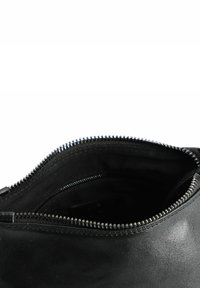 Borsa in pelle nera con chiusura a zip. Texture liscia, design semplice e dettagli della cerniera argentati in contrasto. L'interno è in tessuto scuro.
