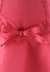 Korallenrosa Stoff mit glatter Textur, mit einer aus dem gleichen Material gefertigten, gebundenen Schleifenakzent an der Taille.