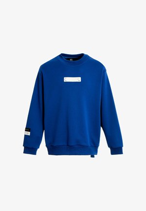 Sudadera azul de mezcla de algodón, con cuello redondo, mangas largas y una etiqueta rectangular blanca con accesorios en la parte delantera.