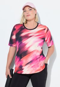 Camiseta atlética de manga corta en un vibrante patrón abstracto en rosa, naranja y negro; cuenta con un cuello redondo y un ajuste relajado.