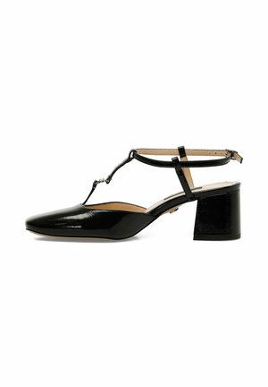 Chaussure en cuir verni noir avec un bout pointu, une bride de cheville et un design en T. Présente un talon épais pour plus de stabilité. Texture lisse, accents minimalistes.