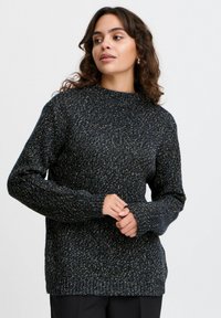 Granatowy sweter wykonany na szydełku z teksturowanym wykończeniem, z wysokim dekoltem i długimi rękawami, zaprojektowany w luźnym kroju z prążkowanymi mankietami.