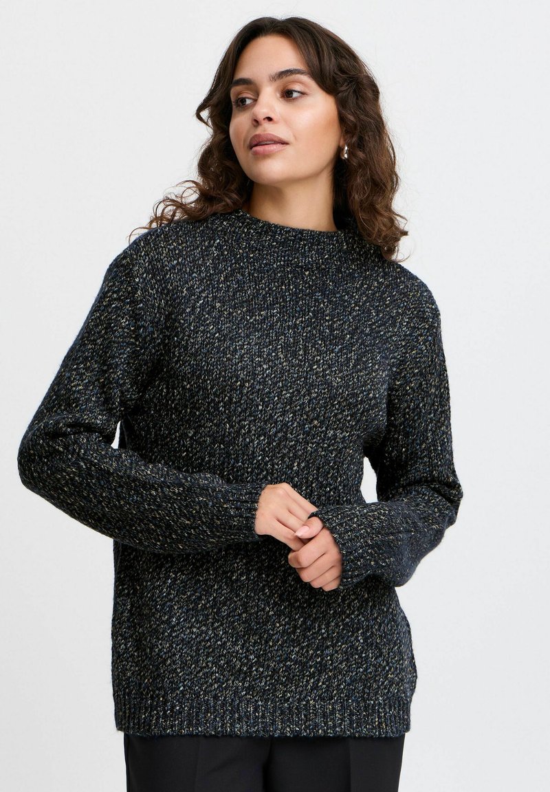 Granatowy sweter wykonany na szydełku z teksturowanym wykończeniem, z wysokim dekoltem i długimi rękawami, zaprojektowany w luźnym kroju z prążkowanymi mankietami.