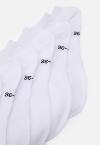 Weiße Knöchelsocken, die in einer Reihe angeordnet sind, mit einem gerippten Bündchen und schwarzem Größenaufdruck "36-" in der Nähe der Zehen auf jeder Socke.