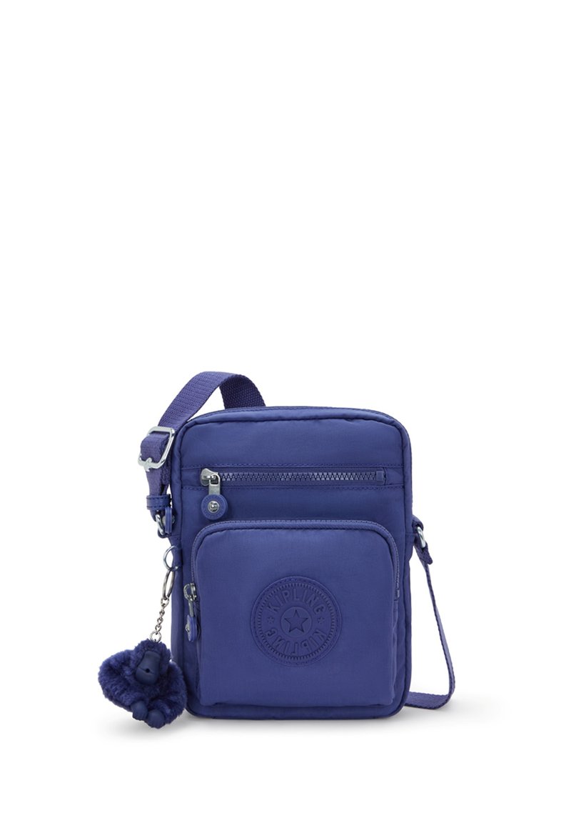 Lila nylon crossbody-väska med justerbar axelrem, framficka med dragkedja och en rund logopatch. Har en nyckelring i pälsliknande material som accent.