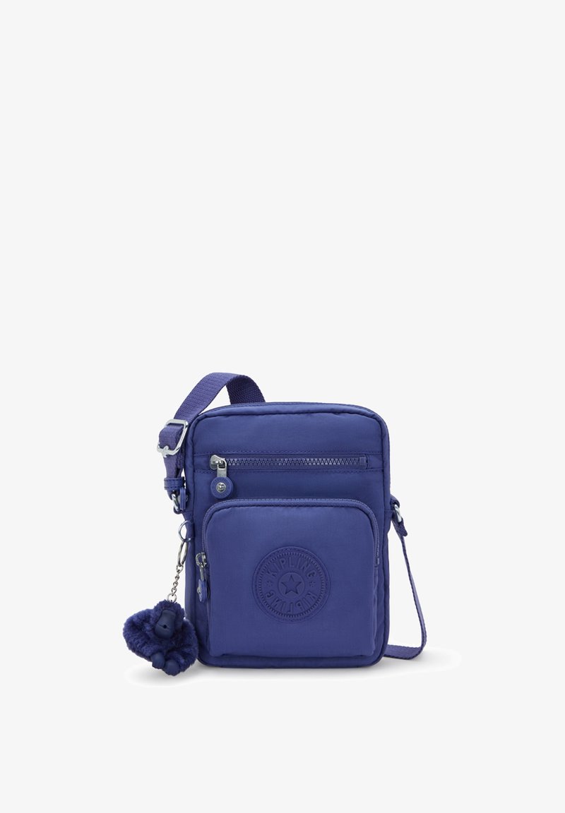 Lila nylon crossbody-väska med justerbar axelrem, framficka med dragkedja och en rund logopatch. Har en nyckelring i pälsliknande material som accent.