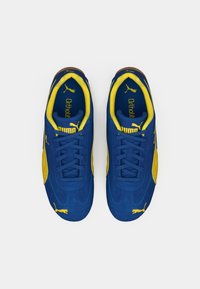 Blauwe en gele sneakers met een bovenwerk van suede, vetersluiting, gewatteerde kraag en rubberen zool; heeft het PUMA-logo op de zijkant en inlegzool.