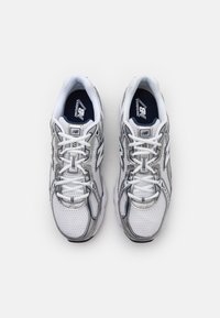 Białe siateczkowe sneakersy z szarymi akcentami, okrągłym noskiem, sznurowane, z wyściełanym kołnierzem i gumową podeszwą. Z logo na języku i boku.