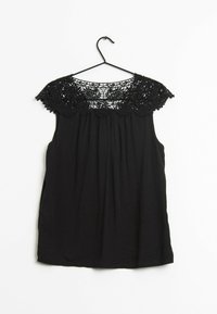 Černý bezramínkový top s krajkovou yoke, plisovaným předním dílem a jemnou texturou, zavěšený na černém háčku na bíl ém pozadí.