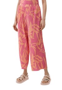 Roze wijde broek met een ribbeltextuur en koraalkleurig loofdruk. Gecombineerd met lichtroze instappers met brede banden.