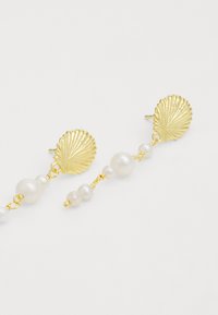 Brincos em forma de concha banhados a ouro com pérolas brancas, apresentando um design pendente e tamanhos alternados das pérolas ao longo da corrente.