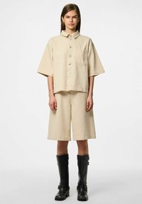 Bežna kratka majica s kratkimi rokavi, ovratnikom in žepom na prsih, v kombinaciji z ustreznimi kratkimi hlačami do kolen. Nosijo se z black škornji do kolen.