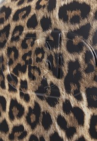 Schwarze Reisetasche mit einem Leopardenmuster, das eine strukturierte Oberfläche mit golden-braunen Flecken aufweist; elegantes Design und ein auffälliger Verschlussbereich.