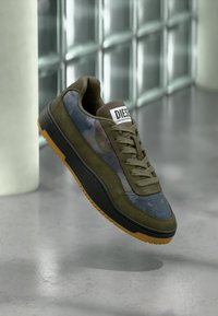 Sneakers verde oliva con tomaia in camoscio e tessuto, suola in gomma nera e suola esterna in gomma naturale. Caratterizzate da una patch con il logo e chiusura con lacci.