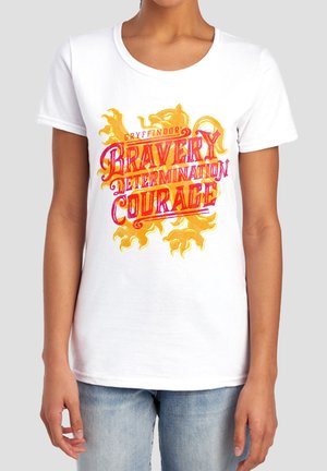 Person wearing a white T-shirt with a yellow lion and red text reading "Gryffindor Bravery Determination Courage" on the front.