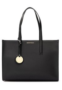 Svart läder tote-väska med dubbla handtag, guldlogoskylta och minimalistisk design. Har en slät textur och rektangulär form.