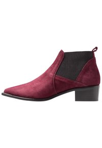 Burgundy suede ankle boot with a pointed toe, elastic side panels, and a low block heel. Features a pull tab at the back.