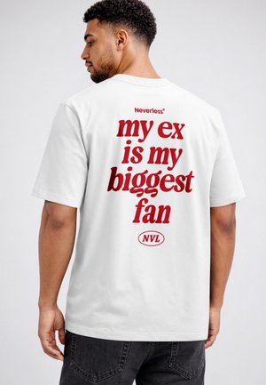 Man with short curly hair wearing a white t-shirt with red text reading "my ex is my biggest fan" on the back.