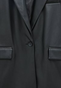Blazer en cuir noir avec revers crantés, fermeture à un bouton, deux poches à rabat et une doublure intérieure noire visible au niveau du col.