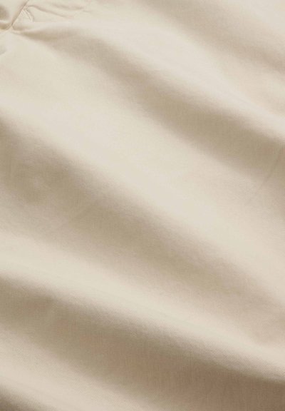 Tissu beige avec de douces plis et une surface lisse légèrement texturée.