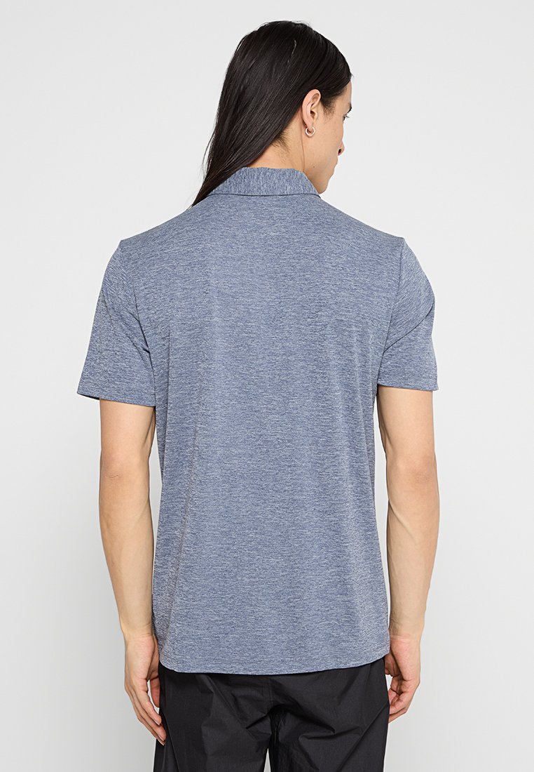 Polo de manga corta en tela azul jaspeada con cuello, que presenta un bajo recto y un diseño de corte relajado.