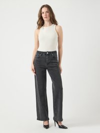 Top blanco de tirantes acanalado combinado con jeans de pierna ancha negros de cintura alta. Tacones negros de punta afinada. Textura suave; diseño minimalista.