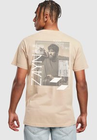Beige bomulds t-shirt med grafisk print på ryggen, som har et foto, tekstbesked "ZAYN" og abstrakte former. Standard pasform med korte ærmer.