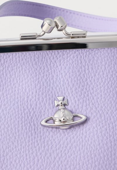 Πορτοφόλι από δέρμα με υφή λεβάντας, με κούμπωμα σε ασημί απόχρωση και μικρό ασημένιο έμβλημα με σφαίρα και δαχτυλίδι στο μπροστινό μέρος.