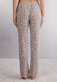 Bloemige pyjamabroek van lichte stof, met een klein rozenpatroon in roze en groen op een witte achtergrond, met een rechte snit en zoomaccenten.