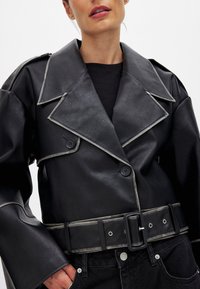 Must musta kunstNahkjakke lai krae, hõbedane äär, topelt nupud ja sobiv vöö. Tekstuuriga materjal ja kellukese varrukad.