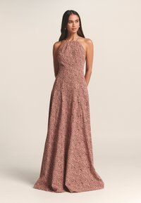 Rožinė halterio tipo suknelė iš minkštos medžiagos su gėlių raštu. Platėjanti silueto linija siekia grindis, išreiškianti sklandžią tekstūrą ir elegantišką dizainą.