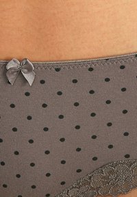 Sivi tkanina s točkicama kratke hlačice sa crnim točkama i sivoj satenskoj mašni na pojasu; završene čipkastim rubom duž dna.