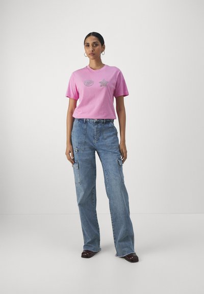 Pink cotton t-shirt featuring decorative design; paired with light blue denim cargo pants with loose fit and multiple pockets.