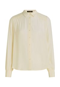 Blusa color crema con design a bottoni, colletto, maniche lunghe e tessuto testurizzato con sottili punti in rilievo.