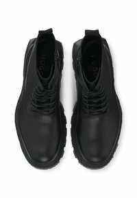Black leather shoes with a smooth finish, round toe, and lacing. Features a zip closure and a chunky rubber sole for traction.