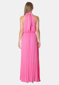 Abito lungo fucsia plissettato con scollo all'americana. Tessuto morbido, fiocco legato sul retro e gonna fluida. Vita elasticizzata per una vestibilità comoda.