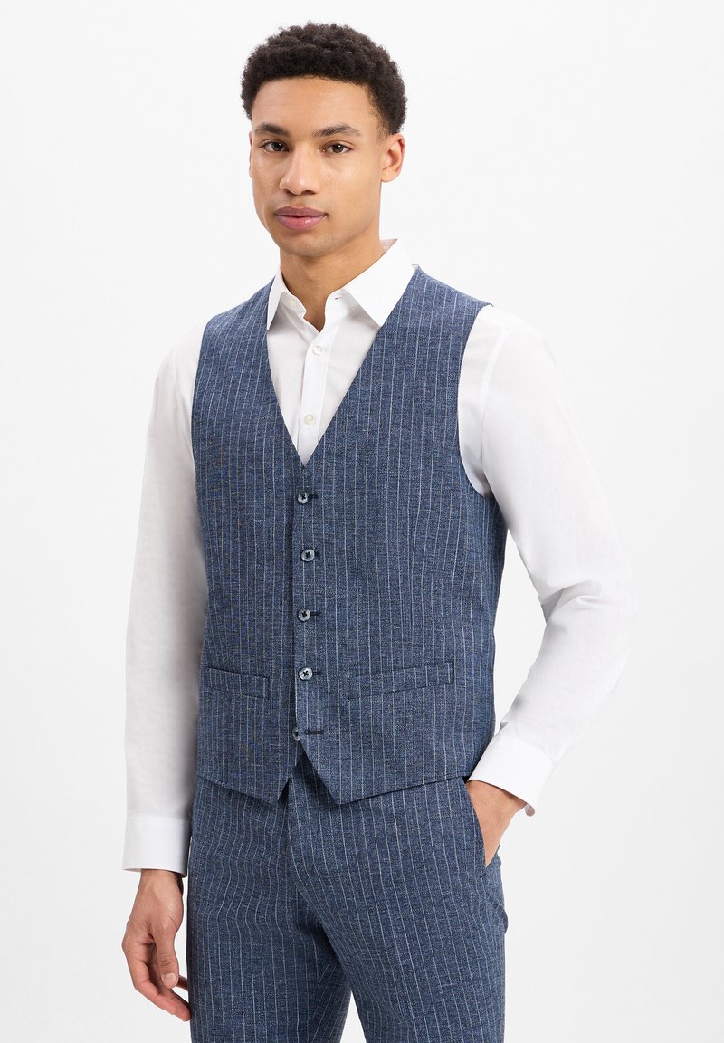 Blau gestreifter Weste aus strukturiertem Stoff, mit V-Ausschnitt, fünf Knöpfen und zwei Seitentaschen, über einem weißen Hemd getragen.