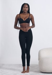 Sort bh og leggings i et blødt, elastisk stof. Toppen har tynde stropper og et enkelt design, mens leggingsene er tætsiddende.
