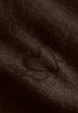 Brown wool fabric with a soft texture, featuring an embossed logo design in a darker shade, highlighting subtle fibers and stitching details.