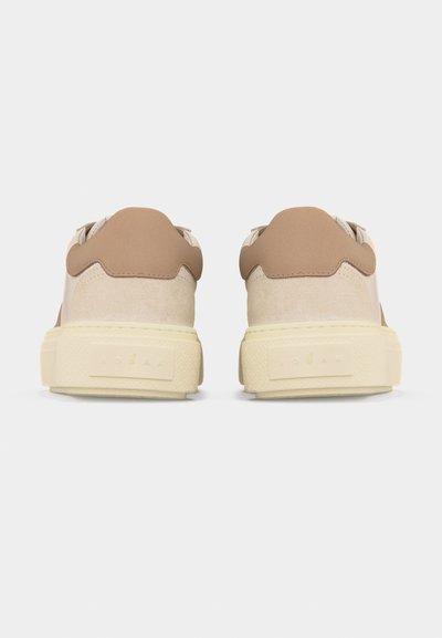 Baskets en daim beige et marron clair vues de dos, dotées de semelles en caoutchouc crème épaisses avec logo embossé.