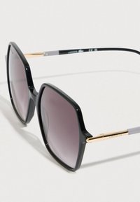 Czarne, duże okulary przeciwsłoneczne z gradientowymi, ciemnymi soczewkami. Charakteryzują się błyszczącym wykończeniem, złotymi detalami na zausznikach oraz szarymi akcentami na ramionach.