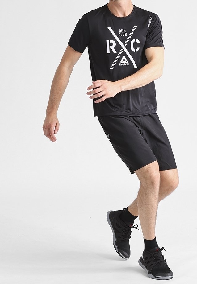 Musta urheilu lyhythihainen paita, jossa on valkoinen "RUN CLUB" ja "RXC" -graafinen painatus, yhdistettynä matching mustiin shortseihin ja mustiin juoksukenkihin.
