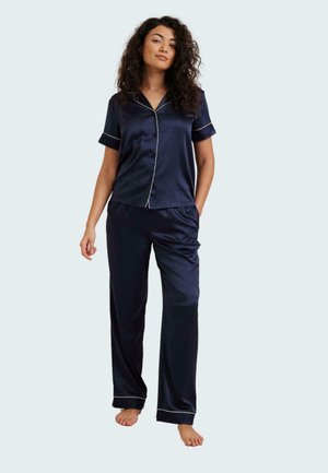 Navy satin pajama set featuring a short-sleeve button-up top with white piping and matching pants, relaxed fit, and smooth texture.