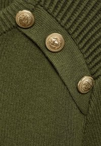 Tessuto a maglia verde oliva con una texture a coste, con tre bottoni dorati con l'emblema del leone lungo la cucitura della spalla.
