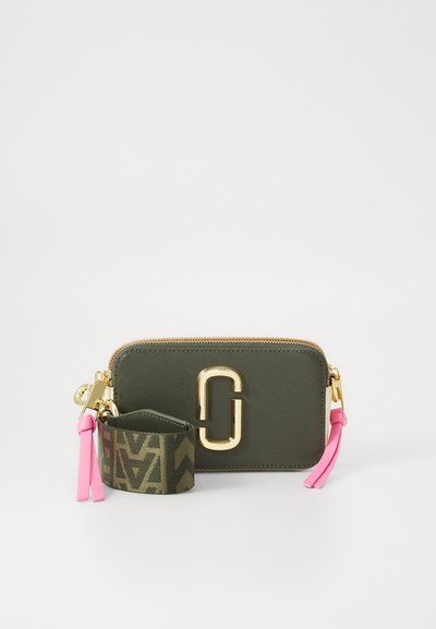 Portefeuille vert olive avec quincaillerie dorée, fermeture éclair et accents roses. Comprend une sangle de poignet à motif pour plus de polyvalence. Texture lisse.