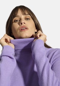 Hellvioletter Rollkragenpullover aus weichem Strickstoff. Mit hohem Kragen und gerippten Bündchen, locker sitzend und mit glatter Textur.